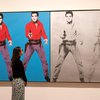 A gallery assistant poses with Andy Warhol's <em>Elvis 1 and 2 1963-4</em> during a press preview for Tate Modern's retrospective on March 10, 2020.